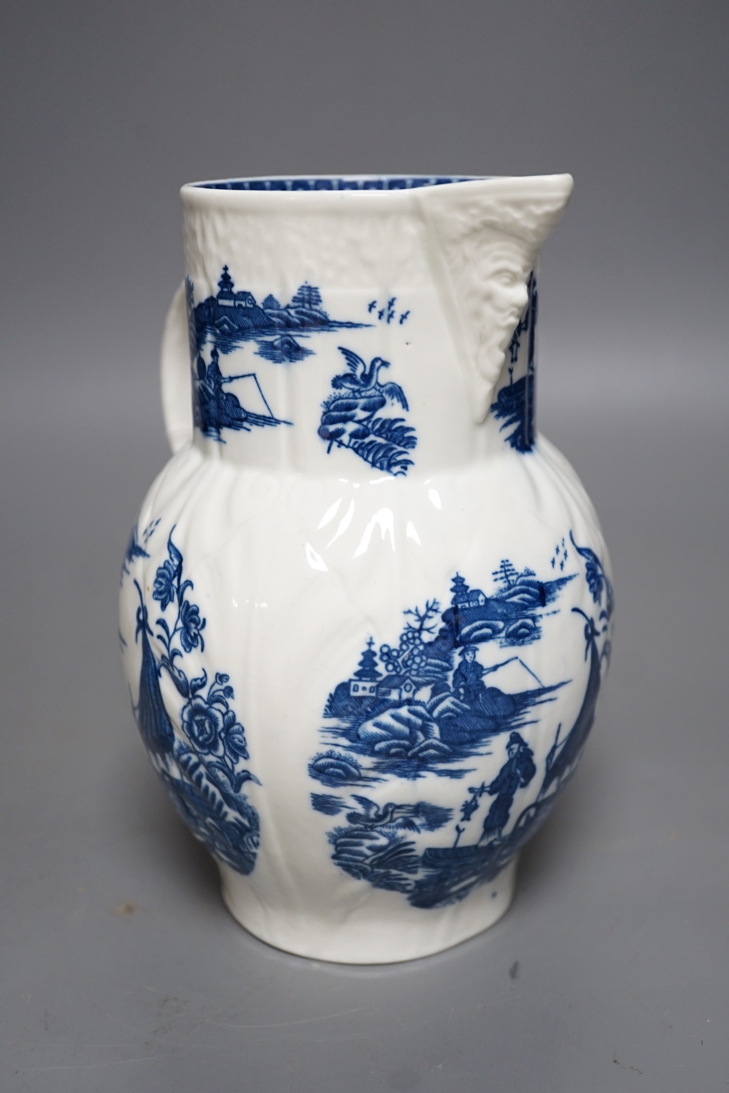 A Caughley baluster mask jug of cabbage leaf moulded shape, printed in underglaze blue with five landscapes of the Fisherman, Sx mark, 19cms high